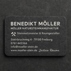 Elegante Visitenkarte eines Natursteinbetriebs mit silberner Schrift auf dunklem Steinpapier und Hammer-Symbol.